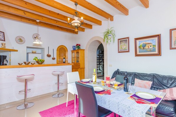 Un comedor con mesa para dos, una zona de bar con taburetes y un sofá.