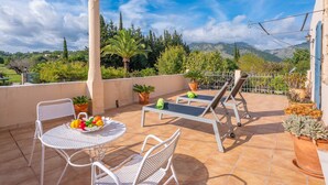 A terrace with a table and chairs, a sun lounger, and potted plants. - Can Salvador - Villa With Private Pool In Moscari (Moscari (selva), Illes Balears)