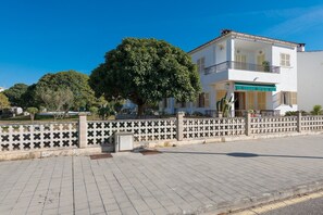A two-story building with a balcony, a tree in front, and a paved walkway. - Ropit - Apartment In Port D'alcúdia. Free Wifi (Port D'alcúdia, Illes Balears)