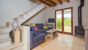 A living room with a sofa, TV, and a fireplace. There is a staircase with a decorative vase and a wooden table.