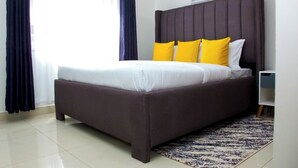Un dormitorio moderno con una cama grande, cabecera oscura y alfombra estampada.