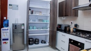Una cocina equipada con refrigerador, dispensador de agua y estufa.