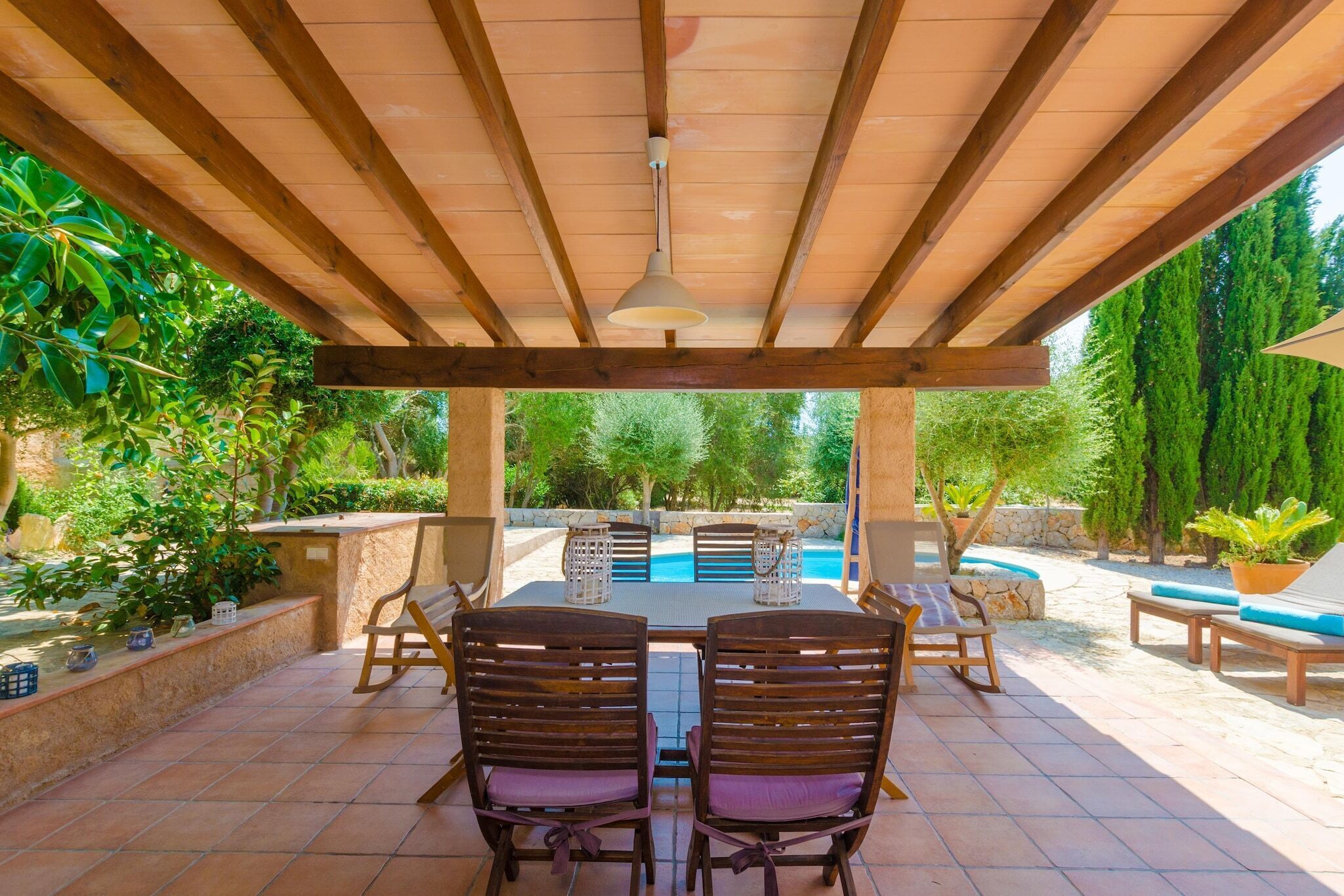 Une terrasse extérieure dotée d’une pergola en bois, d’une table de billard et de coins salon.