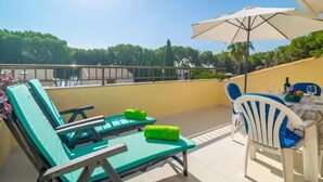 A rooftop terrace with lounge chairs, a table with chairs, and a large umbrella. - Llepol - Apartment In Port D'alcúdia. Free Wifi (Port D'alcÚdia, Illes Balears)
