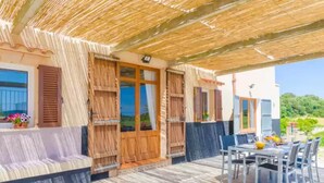 A covered outdoor seating area with a table and chairs, a wooden door, and a view of the landscape. - Es Pont Den Teulari Nou - Villa With Private Pool (Manacor, Illes Balears)