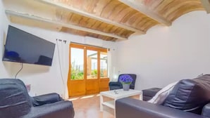 A living room with a flat-screen TV mounted on the wall, a sofa, a coffee table, and a chair. - Es Pont Den Teulari Nou - Villa With Private Pool (Manacor, Illes Balears)