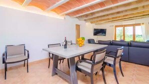 A dining area with a table and chairs, a sofa, and a TV mounted on the wall. - Es Pont Den Teulari Nou - Villa With Private Pool (Manacor, Illes Balears)