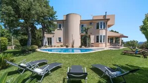 Une maison moderne à deux étages, dotée d’une piscine, entourée d’une pelouse bien entretenue et d’arbres.
