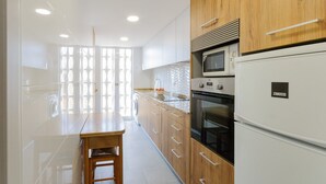 A modern kitchen with wooden cabinets, a built-in oven, a microwave, and a refrigerator.