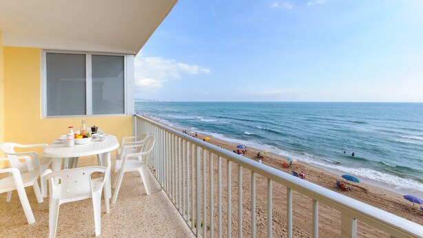 A balcony with a view of the beach and ocean.