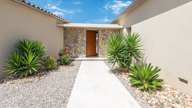 A pathway leading to a door with a stone wall backdrop, surrounded by desert plants and a gravel path. - Can Colomer Ferragut  - Villa With Private Pool (Artà, Illes Balears)