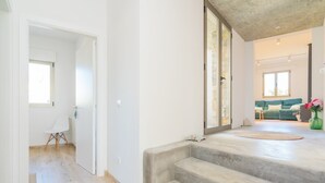A spacious living area with a staircase leading to an upper floor, a green sofa, and a view of the outdoors. - Can Colomer Ferragut  - Villa With Private Pool (Artà, Illes Balears)