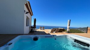 A rooftop pool with clear blue water, surrounded by lounge chairs and umbrellas, overlooking a scenic view. - Villa Vue Mer 180 - Face aux îles d’Or (Carqueiranne)
