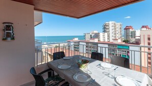A balcony with a table set for dining, overlooking a cityscape and the sea. - Torres Del Mar - Apartment In Grau I Platja (Playa De Gandia, Valencia)