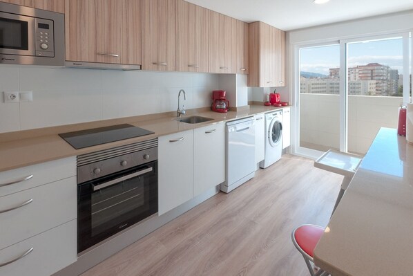 A modern kitchen with a microwave, oven, sink, and washing machine.