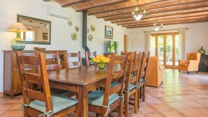 A dining area with a wooden table and chairs, a bowl of fruit, and a television. - Can Mostatxet - Villa With Private Pool. Free Wifi (Can Picafort, Illes Balears)