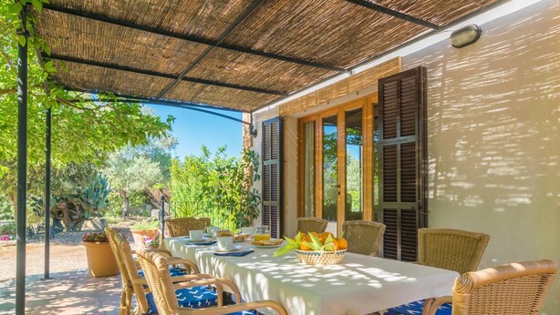 A covered outdoor dining area with wicker chairs and a table set for breakfast. - Can Mostatxet - Villa With Private Pool. Free Wifi (Can Picafort, Illes Balears)