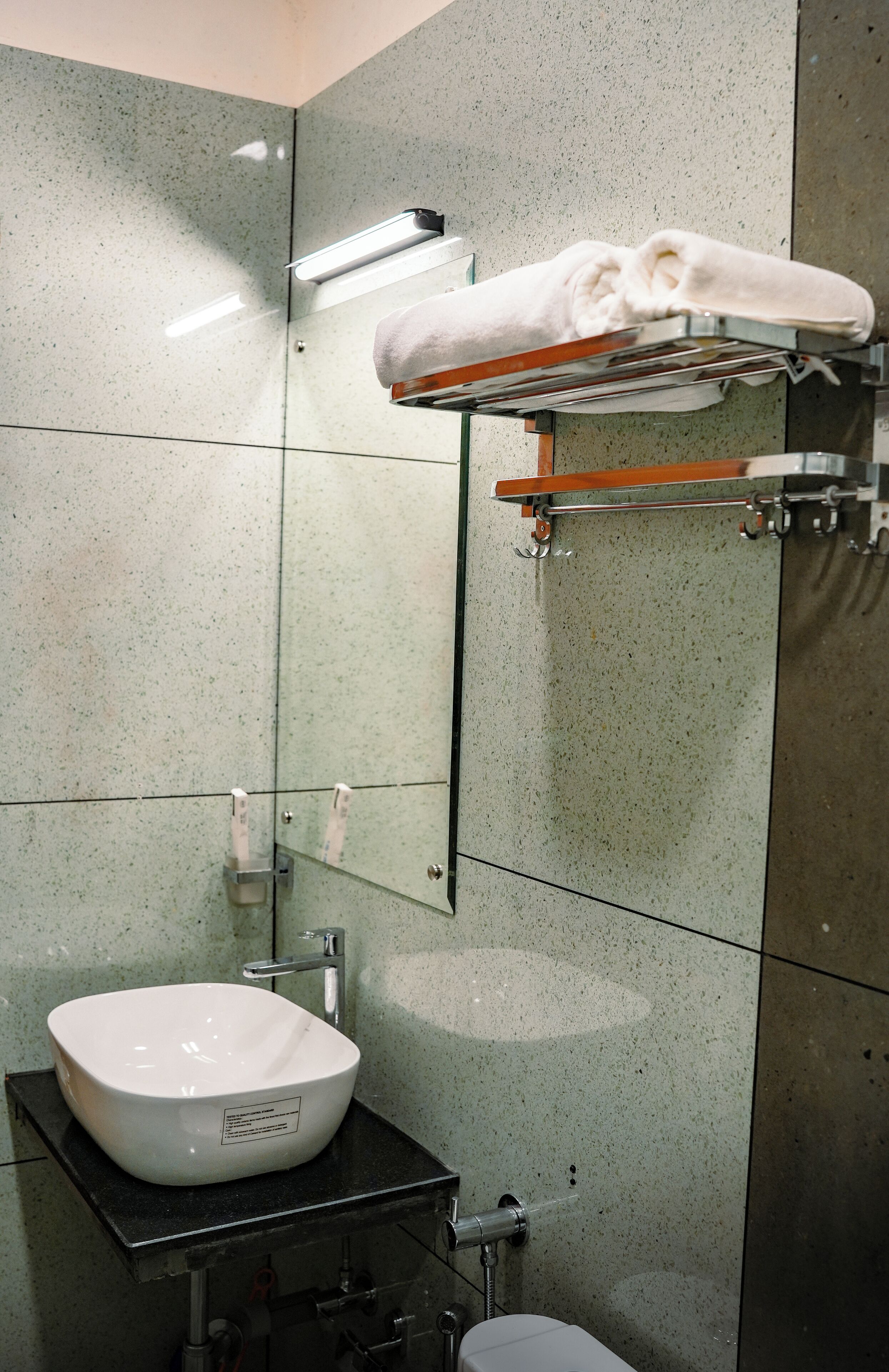 Un baño con lavamanos blanco, toallero y espejo.