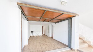 An interior space with a tiled floor, a wooden ceiling, and a staircase on the right.