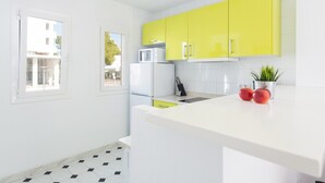 A modern kitchen with white cabinets, a white countertop, and a window providing natural light.
