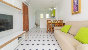 A living room with a sofa, TV, and dining area with chairs and a table.