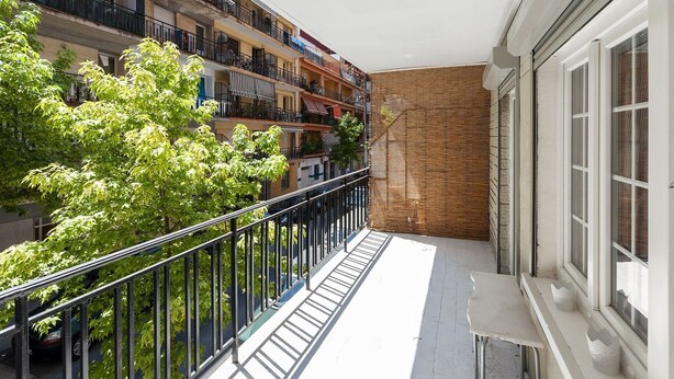 A balcony with a metal railing, a small table, and a window with white shutters. - Samba - Apartment In Gandia (Gandia, Valencia)