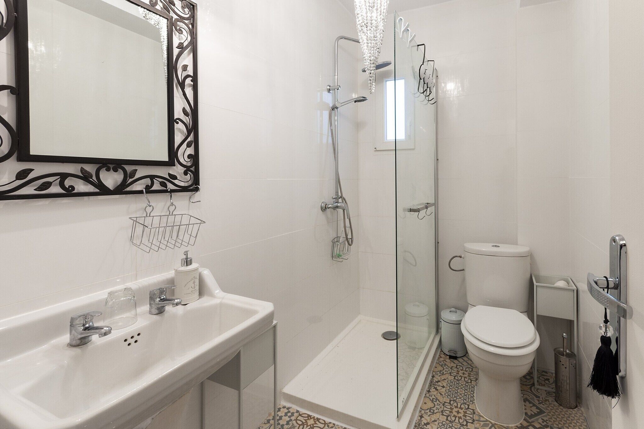 Un baño con ducha de vidrio, lavamanos blanco y un inodoro.