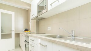 A modern kitchen with white cabinetry, a stainless steel sink, and a built-in oven. - Ses Roques De Cala Bona - Apartment In Cala Millor (Cala Millor, Illes Balears)