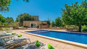 Une piscine avec des chaises longues et, en arrière-plan, un bâtiment en pierre.