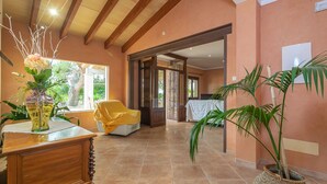 A spacious room with a wooden ceiling, a large window, a dining table with chairs, and a potted plant. - Can Ribas - Villa With Private Pool. Free Wifi (Can Picafort, Illes Balears)