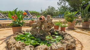 A pool area with lounge chairs, potted plants, and a decorative rock structure. - Can Ribas - Villa With Private Pool. Free Wifi (Can Picafort, Illes Balears)