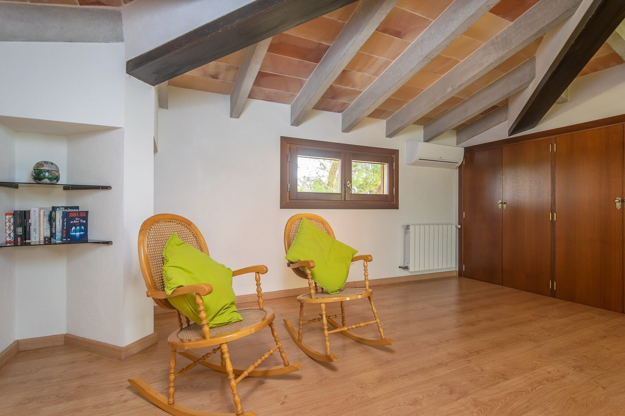 A room with two rocking chairs, a wooden floor, a window, and a radiator.