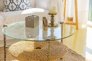 Una mesa con cubierta de vidrio, un posavasos tejido, un candelabro y un libro.