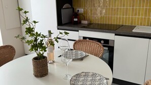 A round dining table with wicker chairs, a bottle of water, and a wine glass on the table. - Beautiful renovated village house in the heart of Provence. (Graveson)