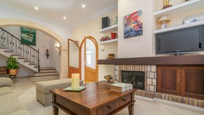 A spacious living room with a fireplace, a staircase, and a television. - Unio 36 - Villa With Private Pool In Ariany (Ariany, Illes Balears)