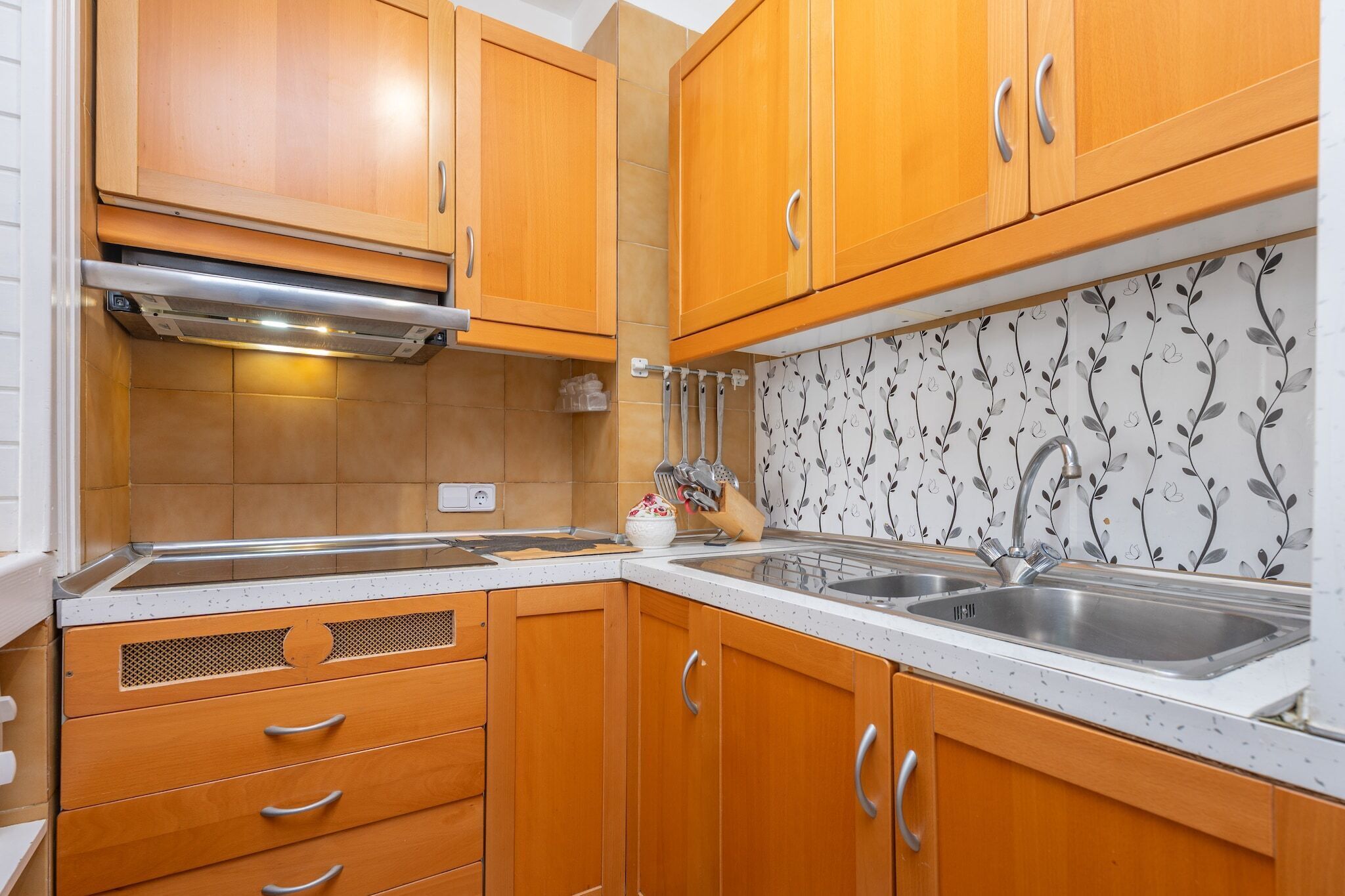A kitchen with wooden cabinets, a stainless steel sink, and a decorative backsplash.