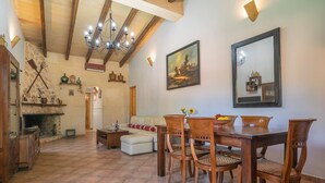 A dining area with a wooden table and chairs, a fireplace, and a painting on the wall.