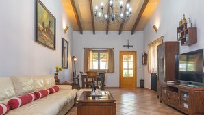 A living room with a sofa, coffee table, TV, wooden cabinet, and a dining area with a table and chairs.