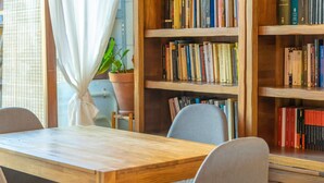 A wooden table with chairs in a room with bookshelves.