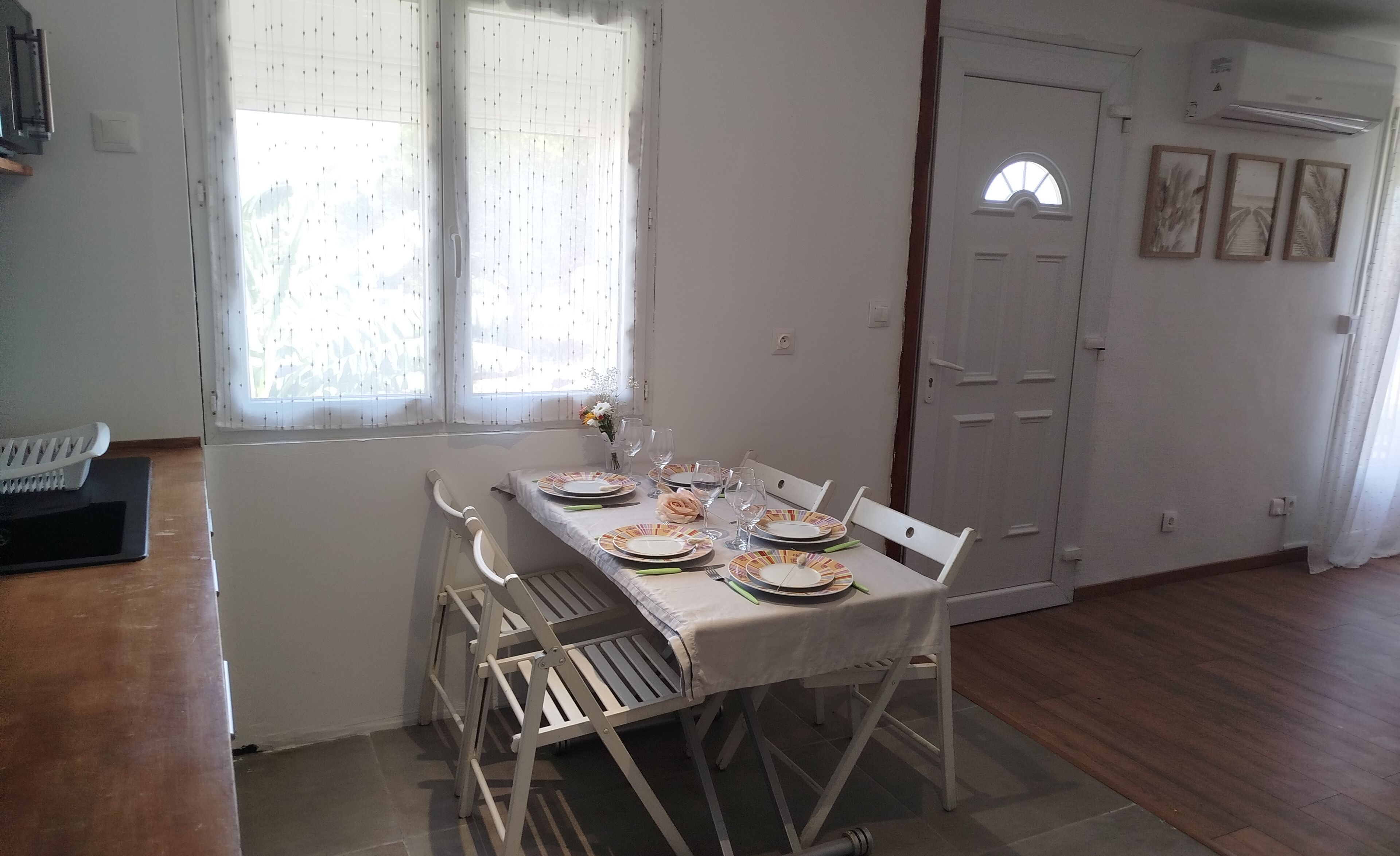 A dining area with a table set for four, chairs, a window with curtains, and a door with a small window.