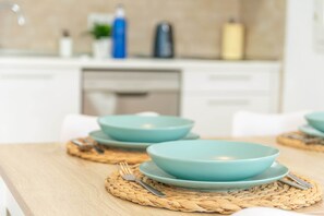 Una mesa de comedor con cuencos y platos color turquesa, un posavasos tejido y un tenedor.