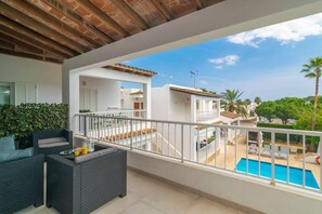 A balcony with outdoor furniture, a pool, and a view of neighboring buildings.
