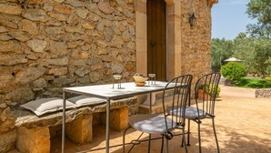 A stone building with a rustic outdoor seating area featuring a table and chairs.