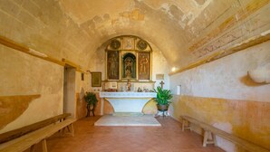 Eine Kapelle mit hoher, gewölbter Decke, einem zentralen Altar und Bänken entlang der Wände.