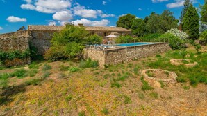 Ein Gebäude aus Stein mit Pool und Außenbereich, umgeben von Grünflächen und Bäumen.