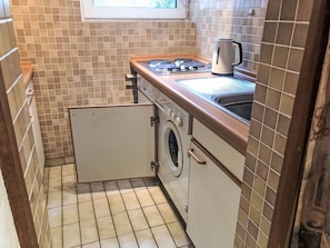 A compact kitchen with a built-in washing machine, a stove, and a sink.