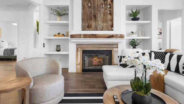 Un salon moderne avec une cheminée, des canapés blancs et des étagères en bois.