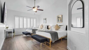 Une chambre à coucher moderne avec un grand lit, un bureau et un ventilateur de plafond.