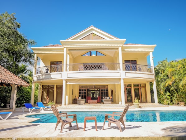 A two-story house with a pool, outdoor seating, and a balcony.