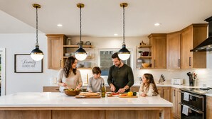 A modern kitchen with wooden cabinets, a central island, and pendant lighting.